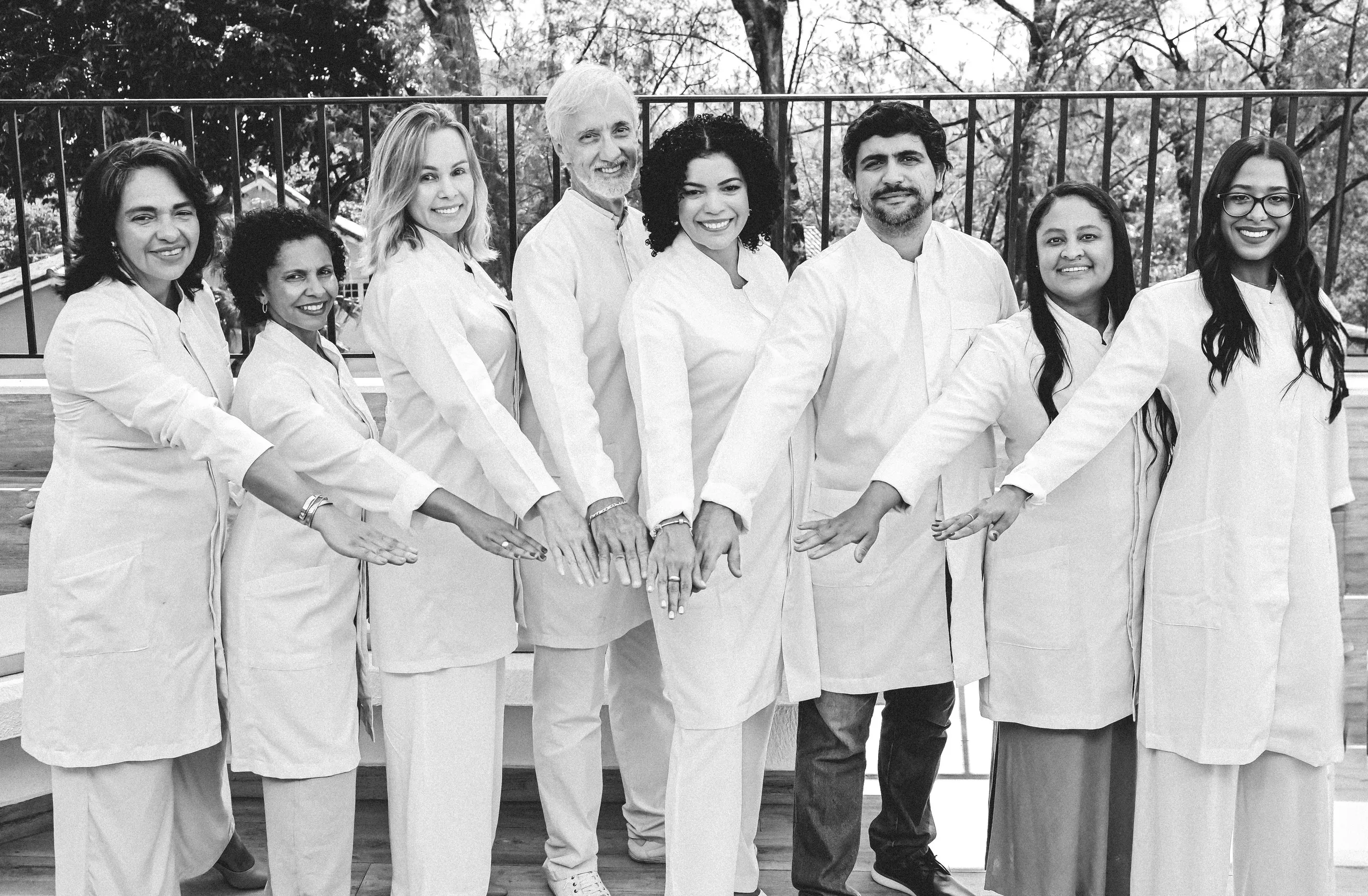 Equipe do Espaço Ana Gil em preto e branco, de mãos dadas